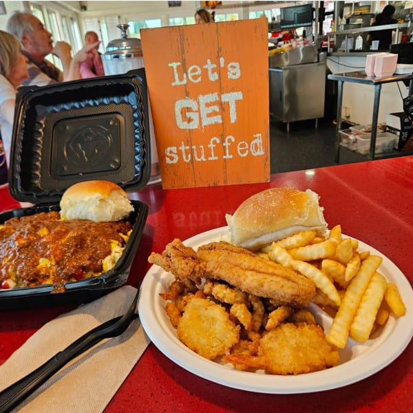 Two plates of food, one with chili and a bun, the other with fried fish, shrimp, and fries.